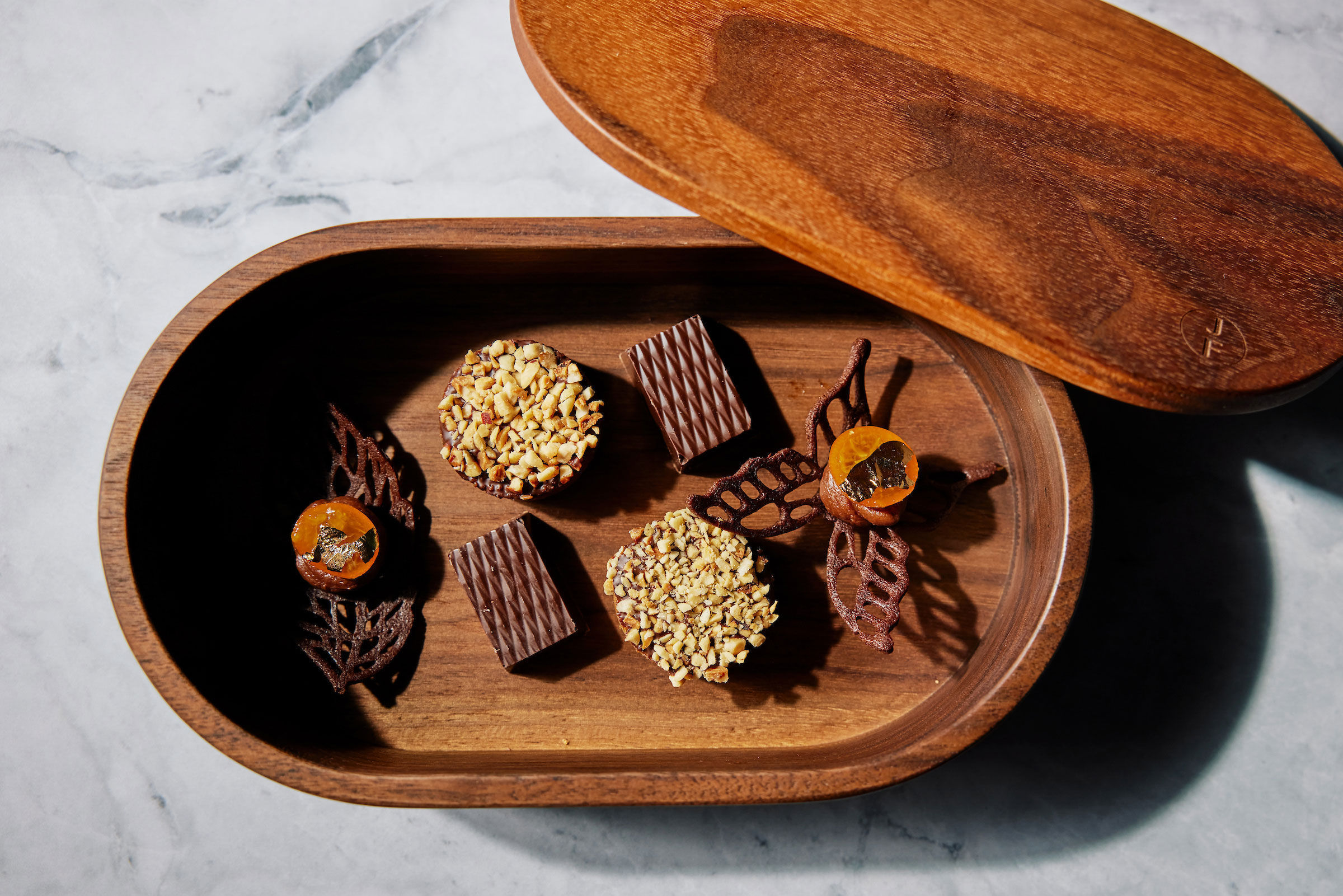 wooden oval box containing decorative chocolates and mignardises for dessert